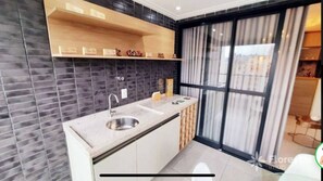 A modern kitchen with a built-in sink, wooden shelves, and a large window with curtains. - Porto Gold Way Apart Porto da Barra Beach à 450m Away (Salvador)