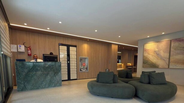 Un hall d’hôtel moderne avec un comptoir d’accueil, un espace salon et une petite table basse.