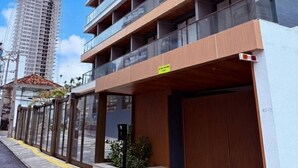 Un bâtiment moderne à plusieurs étages, doté de grandes fenêtres et d’une entrée sécurisée par un portail.