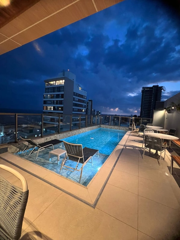 Une piscine située sur le toit, offrant une vue sur les gratte-ciel de la ville au crépuscule.