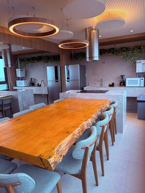 Une cuisine moderne dotée d’un îlot central, d’appareils électroménagers intégrés et de luminaires suspendus.