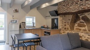 Moderni keittiö, jossa on kiviseinä, ruokailutila pöytineen ja tuoleineen sekä sisäänrakennettu uuni.