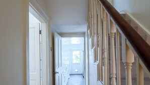 A hallway with wooden flooring, white walls, and a wooden staircase with a balustrade. - Elegant 3BR Victorian Retreat, Free Parking (Kingston Upon Thames)