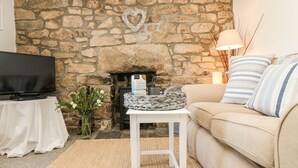 Una sala de estar con chimenea de piedra, un televisor, un sofá y una mesita con una cesta.