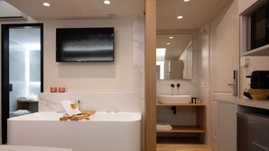 A modern bathroom with a freestanding bathtub, a large mirror, and a flat-screen TV mounted above the sink. - Hanim Boutique |Old Town lux Studio with hot tub 2, Studio (Chania)