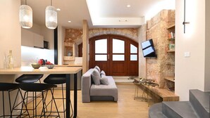 Une cuisine moderne avec un mur en pierre, une porte en bois et un téléviseur fixé au mur.
