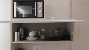 Une petite cuisine équipée d’un four à micro-ondes, d’une bouilloire et d’une petite cuisinière.