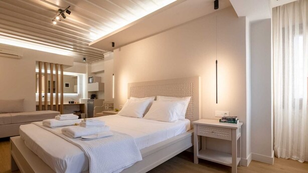 Une chambre d’hôtel moderne avec un grand lit, une table de chevet, un canapé et un miroir.