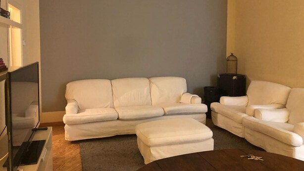 Sala de estar com um sofá bege, um sofá branco e uma mesa de centro.