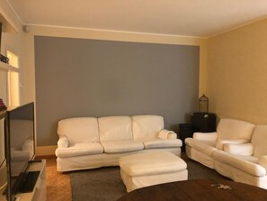 Sala de estar com um sofá bege, um sofá branco e uma mesa de centro.
