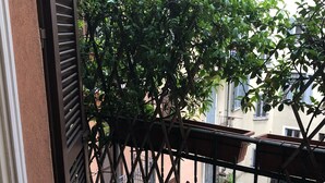 Varanda com vista para uma árvore e prédios vizinhos.