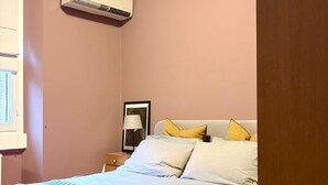 Quarto com cama, mesa de cabeceira, abajur e ar condicionado.