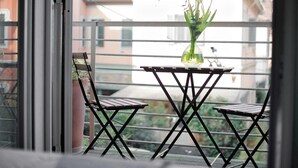 A balcony with a small table and two chairs, a potted plant, and a vase with flowers. - w Modern 1BR w Balcony in Porta Venezia (Milan)