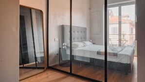 A bedroom with a large bed, a glass partition, and a view of the outside. - w Modern 1BR w Balcony in Porta Venezia (Milan)