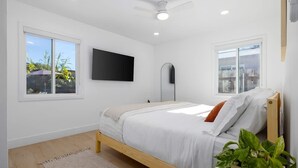 Um quarto moderno com cama de madeira, televisão de tela plana e ventilador de teto.