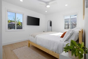 A modern bedroom with a wooden bed, a flat-screen TV, and a ceiling fan. - Carlsbad Bungalow Large Backyard (Carlsbad)