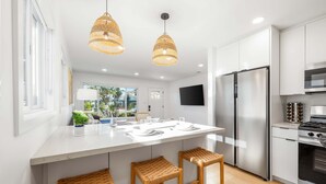 Cocina moderna con isla central, electrodomésticos de acero inoxidable y taburetes de mimbre.