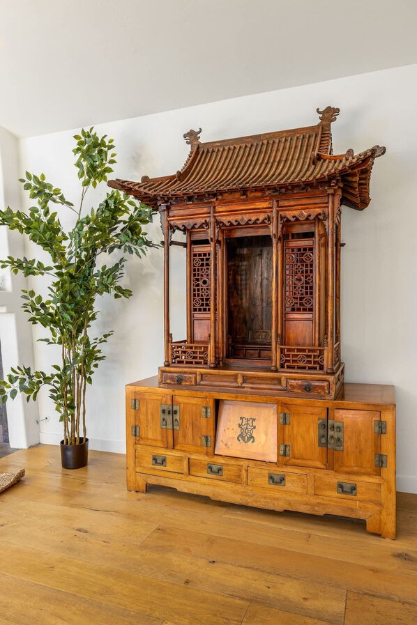 Un meuble traditionnel en bois, orné de sculptures complexes et surmonté d’une structure décorative en guise de toit.