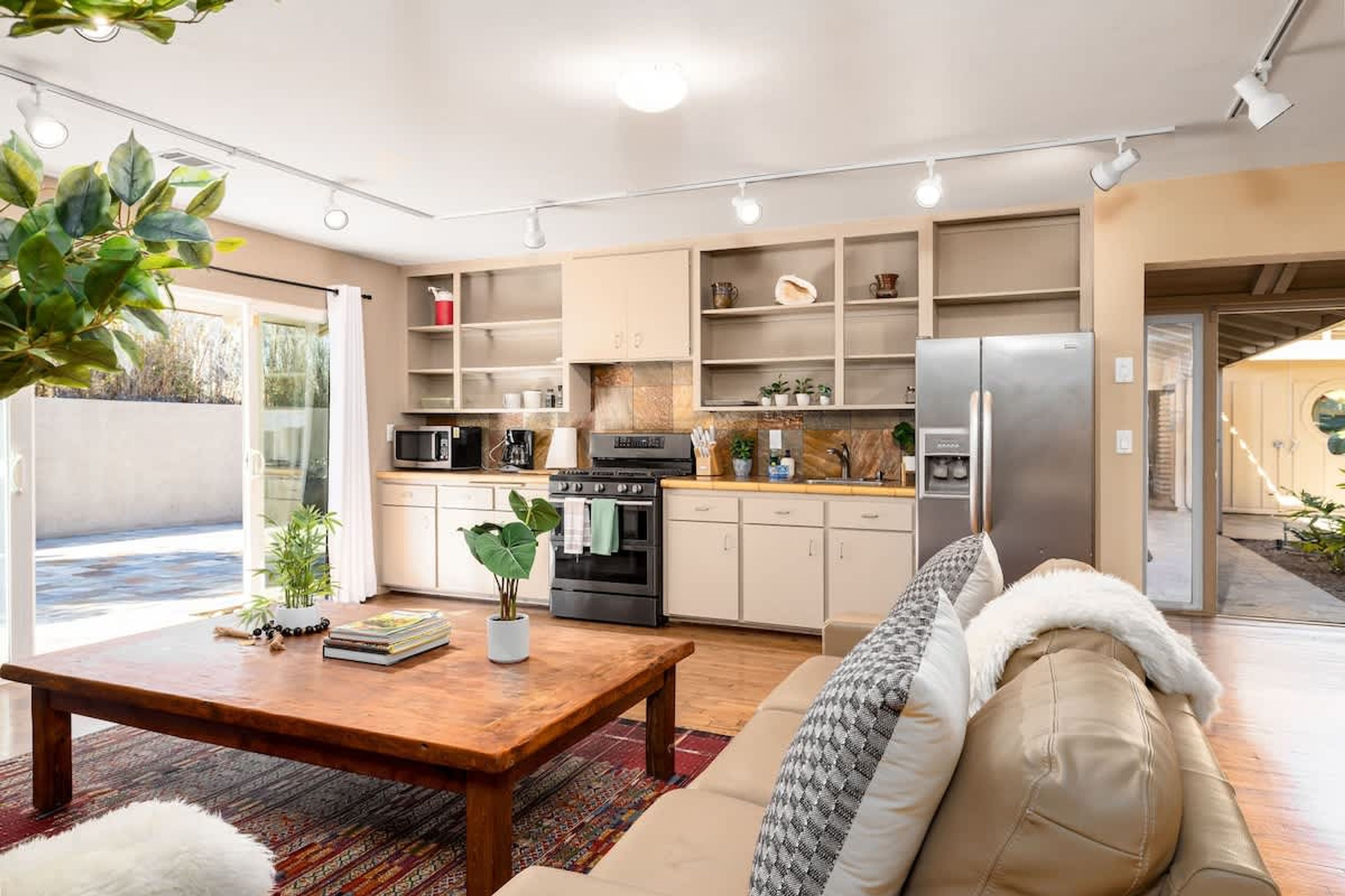 Eine moderne Küche mit integrierten Geräten, ein Essbereich mit einem Holztisch und ein Wohnzimmer mit einer Couch.