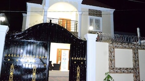 A gated entrance to a building with a white facade and a black gate with gold accents. - Janhas Senegambia Villa Rental 3 With Free Wi-fi (Serrekunda)