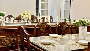 A dining area with a glass table, wooden chairs, and a chandelier. - Palace View Royal Home (Cairo)