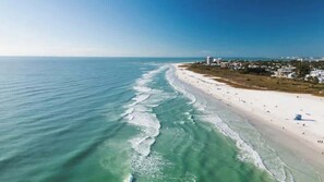 An aerial view of a beach with clear waters, a sandy shore, and buildings in the background. - Siesta Key 3-Story Retreat- Pool, Hot Tub, Balcony (Sarasota)
