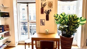 A room with a wooden desk, a large potted plant, and decorative wall art. - Flat 1 Modern Marylebone Apartment with Balcony (London)