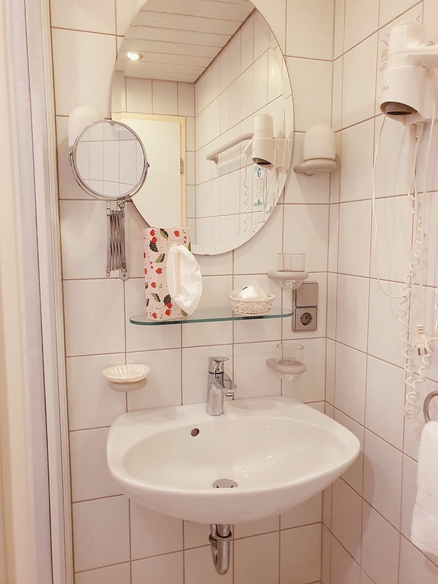 A bathroom with a white sink, a mirror, a hairdryer, and a towel rack.