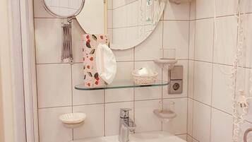 A bathroom with a white sink, a mirror, a hairdryer, and a towel rack.