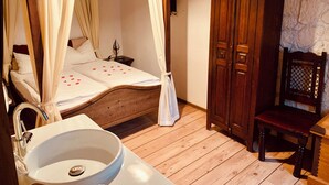 A four-poster bed with a canopy, a wooden wardrobe, a wooden chair, and a white sink. - Gasthof Sonne (Schiltach)