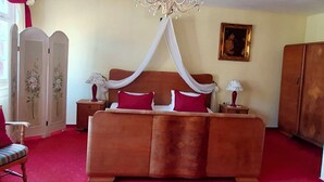 A bedroom with a four-poster bed, a chandelier, a painting on the wall, and a wardrobe. - Gasthof Sonne (Schiltach)