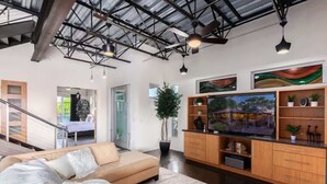 A modern living room with a sofa, TV, wooden cabinets, and a ceiling with exposed beams. - Vantage - Rooftop Patio - Heart of Old Town (Scottsdale)