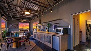 A modern kitchen with a central island, pendant lighting, and a view of the sunset. - Vantage - Rooftop Patio - Heart of Old Town (Scottsdale)