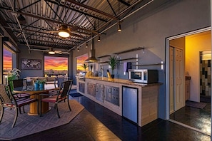 A modern kitchen with a central island, pendant lighting, and a view of the sunset. - Vantage - Rooftop Patio - Heart of Old Town (Scottsdale)