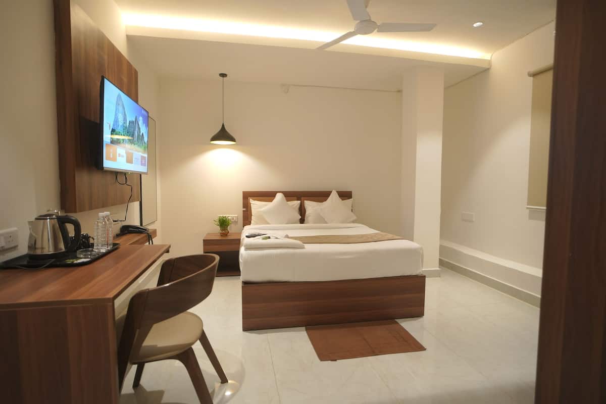 Ein modernes Hotelzimmer mit Bett, Schreibtisch, Stuhl und einem an der Wand befestigten Fernseher.