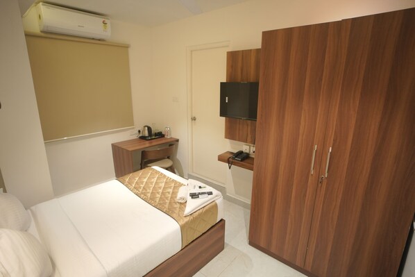 Een hotelkamer met een bed, een bureau, een kledingkast en een televisie.