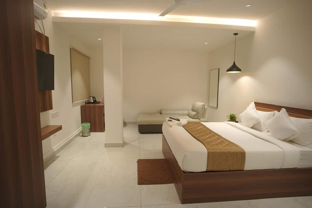 Ein modernes Hotelzimmer mit einem großen Bett, einem Holzkopfende, einem Nachttisch, einem Spiegel und einem Deckenventilator.