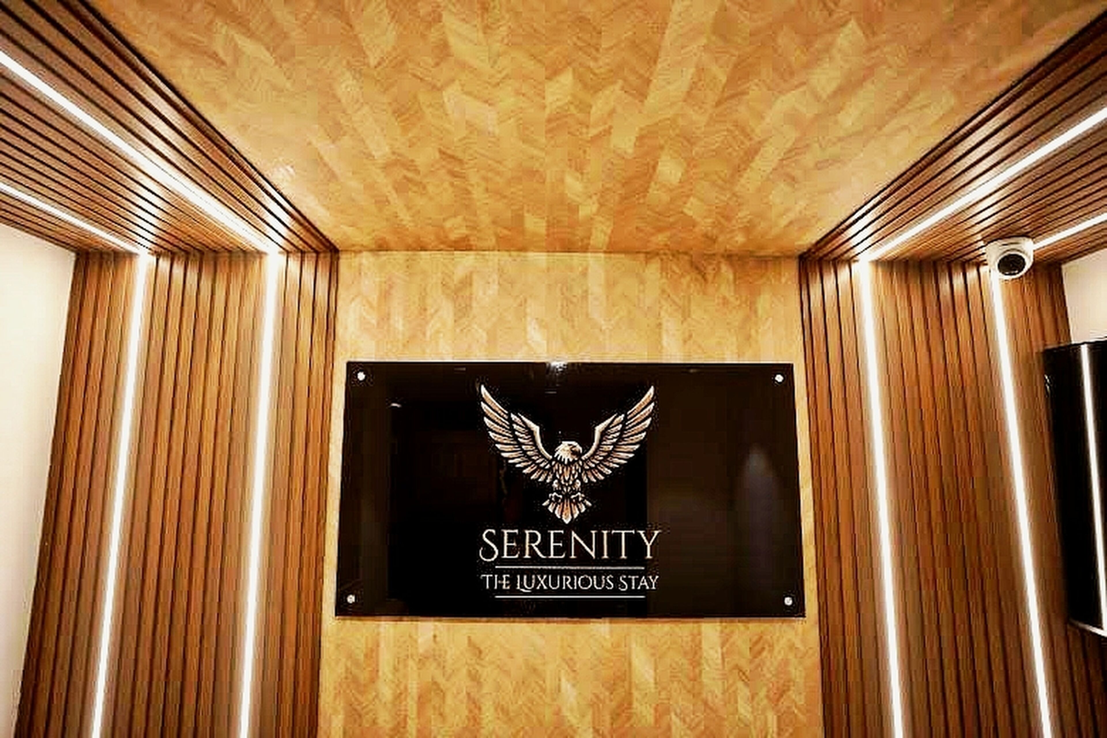 A sign with an eagle emblem and the words 'SERENITY THE LUXURIOUS STAY' on a wall.