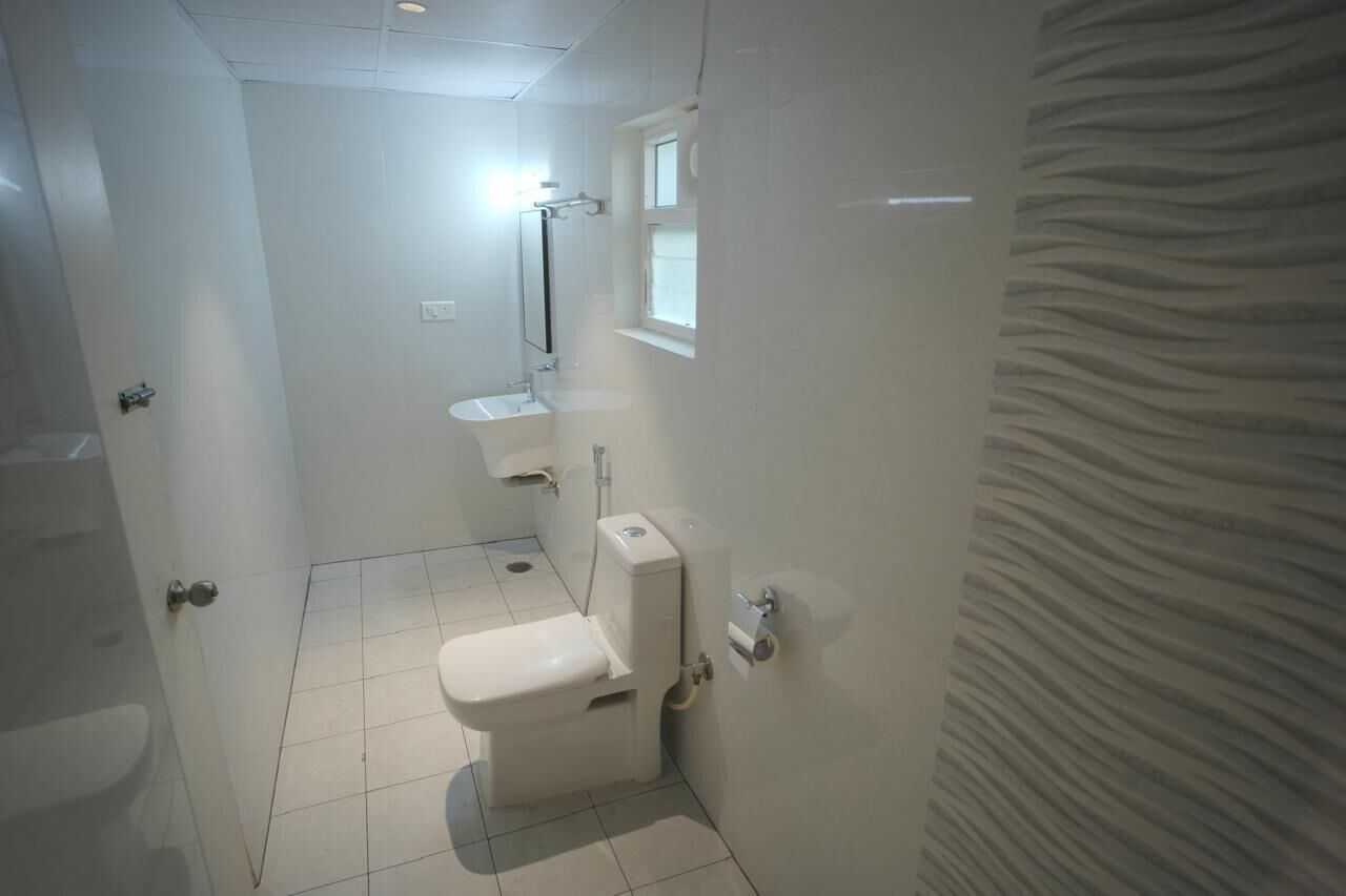 A small, compact bathroom with a toilet, sink, and mirror.