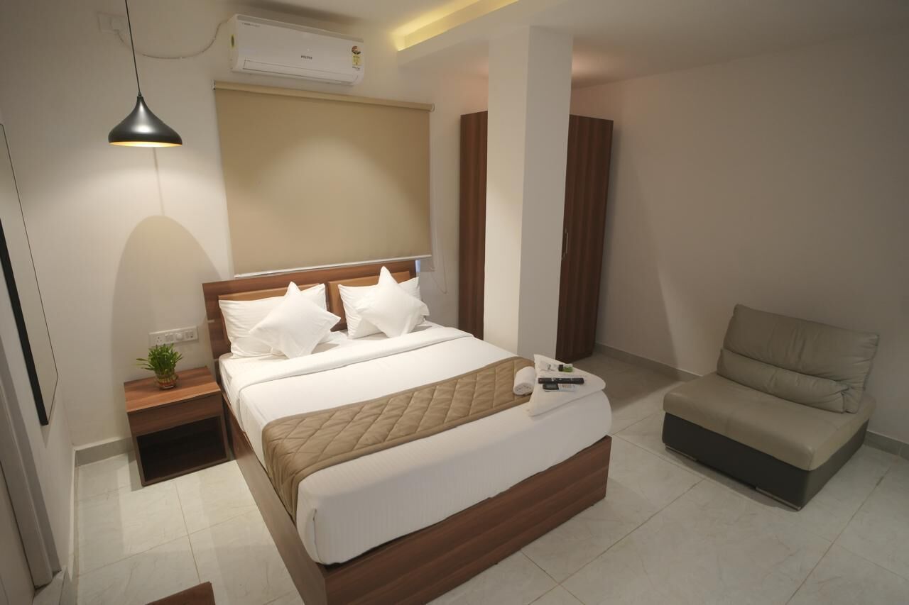 Une chambre d’hôtel moderne, dotée d’un grand lit, d’une table de chevet avec une lampe, d’un canapé et d’un appareil de climatisation.