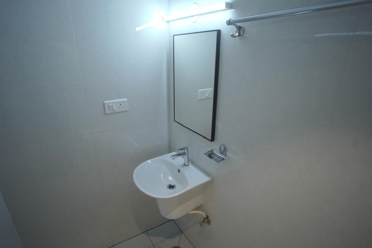 Een badkamer met een witte wastafel, een spiegel en een lamp boven de spiegel.