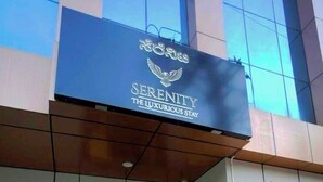 A hotel entrance with a sign reading 'Serenity The Luxurious Stay.' There are steps leading up to the entrance, flanked by potted plants. - Serenity the luxurious stay (Bengaluru)
