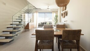 Ein modernes Interieur mit Essbereich, einer Glaskonstruktion als Treppe und Blick ins Freie.