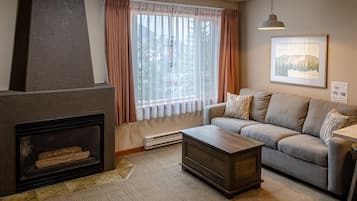 Ein Wohnzimmer mit Kamin, einer Couch, einem Couchtisch und einem Fenster mit Vorhängen.