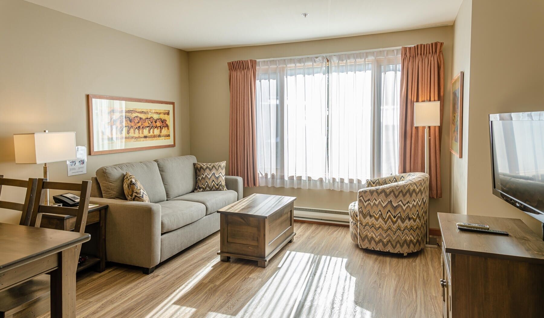 Una sala de estar moderna con sofá, sillón, mesa de centro y televisor.