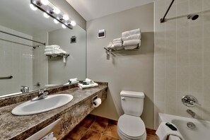 A modern bathroom with a double sink, toilet, and shower. - Cahilty #460 Hotel Room (Sun Peaks)