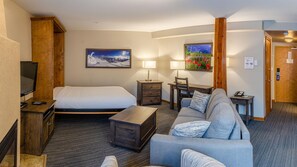 A hotel room with a bed, a sofa, a desk, a TV, and two lamps. - Cahilty #332 Hotel Room (Sun Peaks)