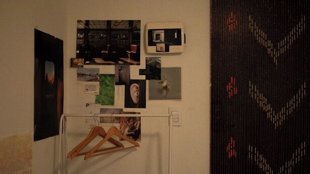 Een muur met verschillende foto's en een kleine, witte koelkast.