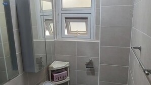 Een kleine badkamer met toilet, wastafel en een raam.