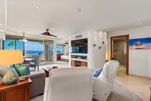 Una sala de estar moderna con un sofá, un televisor y un comedor con vistas.